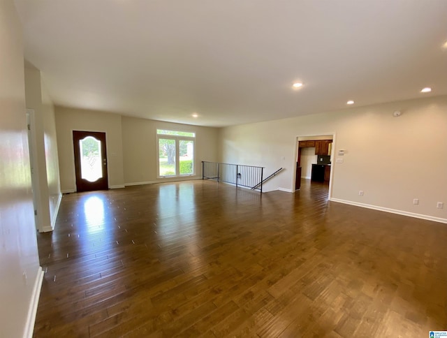 unfurnished living room featuring baseboards, dark wood-style flooring, and recessed lighting