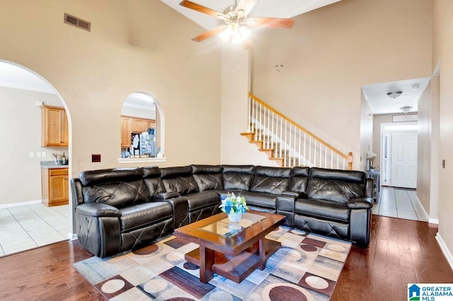 living area with wood finished floors, visible vents, ceiling fan, and a high ceiling
