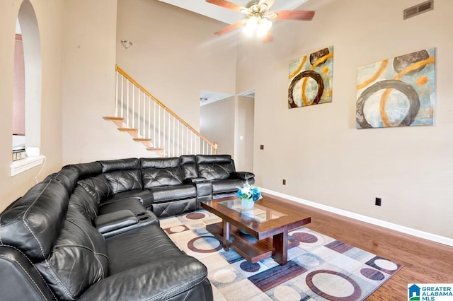 living area featuring wood finished floors, visible vents, arched walkways, baseboards, and ceiling fan