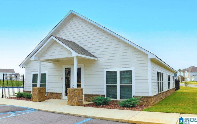 back of property with stone siding, fence, and a yard