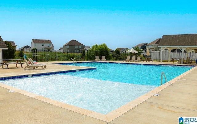 community pool with fence, a patio area, and a residential view