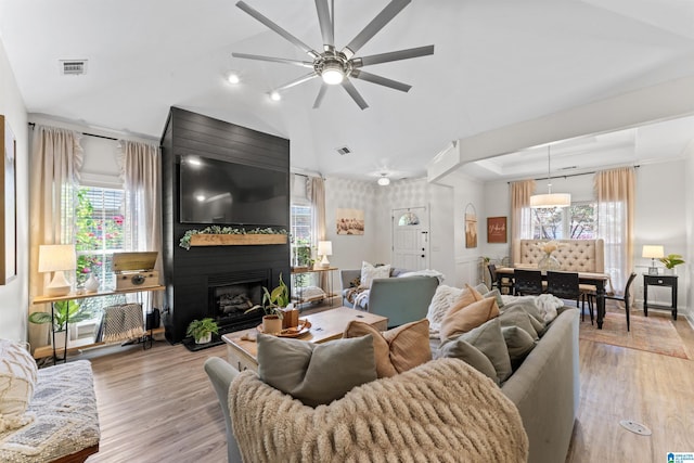 living room featuring light wood-type flooring, a ceiling fan, visible vents, and a wealth of natural light