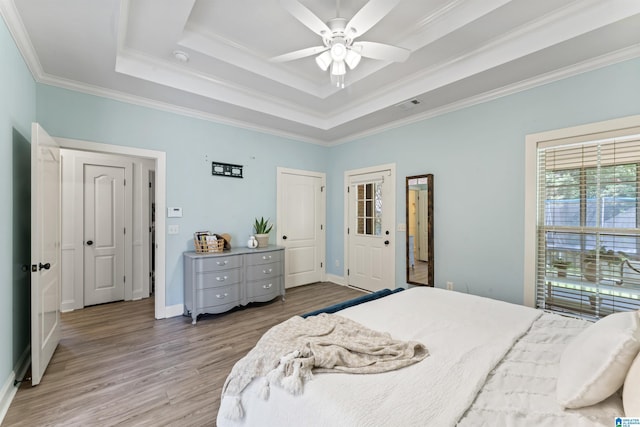 bedroom featuring ornamental molding, wood finished floors, visible vents, and a raised ceiling