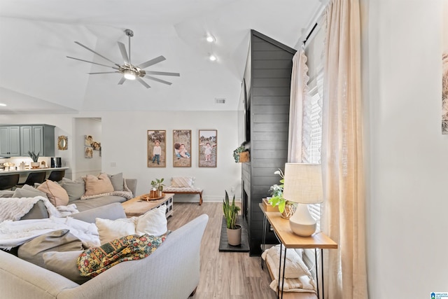 living room with baseboards, visible vents, light wood-style floors, lofted ceiling, and a ceiling fan
