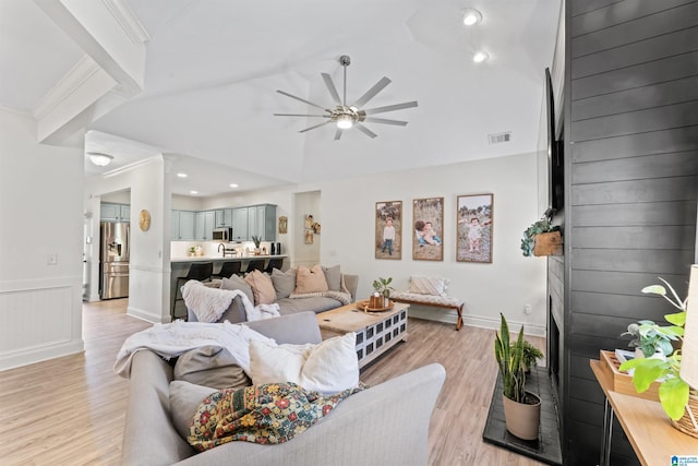 living room featuring ceiling fan, lofted ceiling, visible vents, and light wood-style flooring