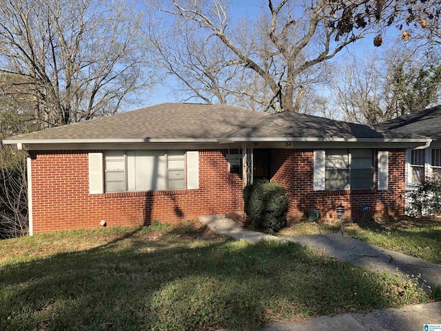 ranch-style house with a front lawn, brick siding, and roof with shingles