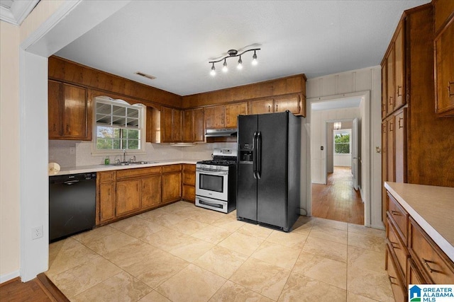1203 Park Ave, Oneonta, AL 35121 - kitchen featuring light countertops, brown cabinetry, under cabinet range hood, visible vents, and black appliances