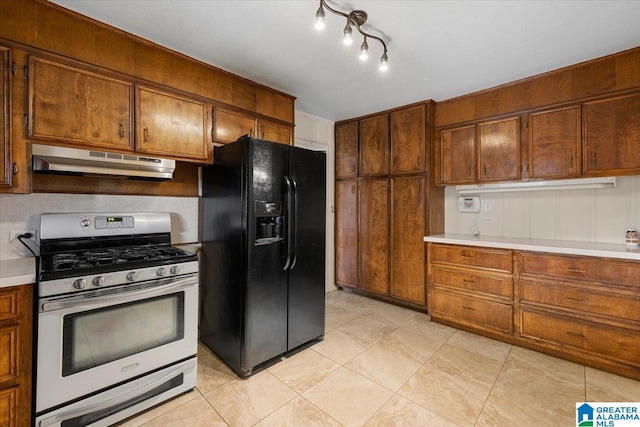 1203 Park Ave, Oneonta, AL 35121 - kitchen with stainless steel gas stove, light countertops, under cabinet range hood, light tile patterned floors, and black fridge