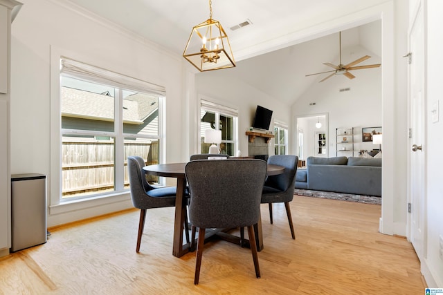 dining area featuring a fireplace, light wood finished floors, visible vents, and plenty of natural light