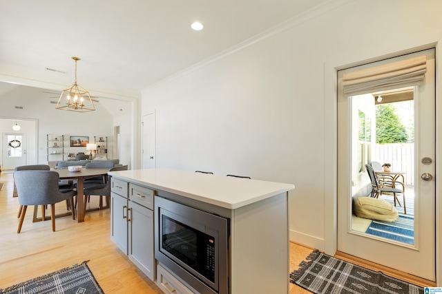 kitchen with crown molding, hanging light fixtures, a chandelier, light countertops, and stainless steel microwave