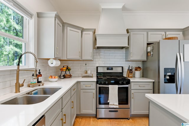 kitchen featuring stainless steel appliances, a sink, backsplash, crown molding, and light countertops