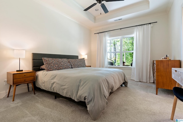 bedroom with light carpet, visible vents, ornamental molding, and a tray ceiling