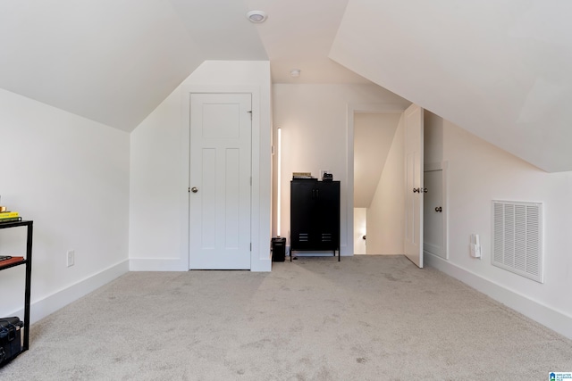additional living space with lofted ceiling, visible vents, and carpet floors