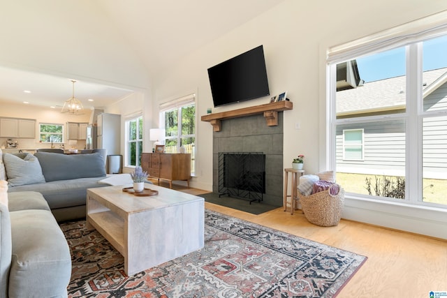 living area with lofted ceiling, a tiled fireplace, wood finished floors, and recessed lighting