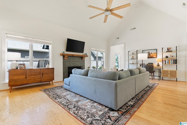 living area featuring a fireplace, wood finished floors, high vaulted ceiling, and ceiling fan