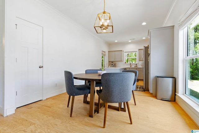 dining space with recessed lighting, light wood-style flooring, crown molding, and an inviting chandelier