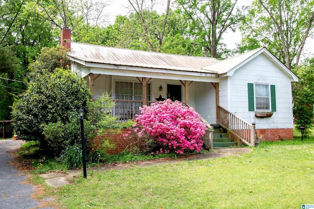 ranch-style house with a front lawn, covered porch, and a chimney