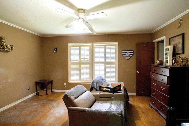 sitting room with a ceiling fan, baseboards, and crown molding