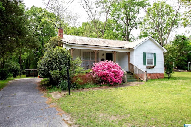 ranch-style home with driveway, a porch, a front yard, and a chimney