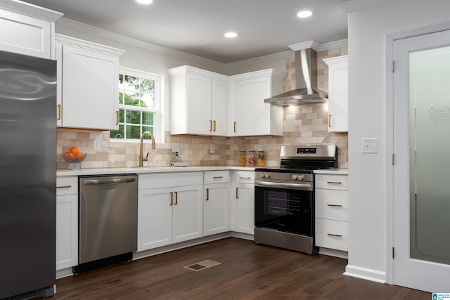 kitchen featuring stainless steel appliances, light countertops, white cabinets, a sink, and wall chimney exhaust hood