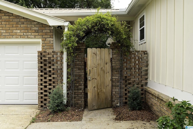 view of side of property with a gate, board and batten siding, brick siding, and an attached garage