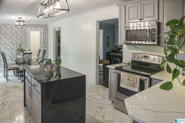 kitchen featuring light stone counters, appliances with stainless steel finishes, decorative light fixtures, ornamental molding, and gray cabinetry