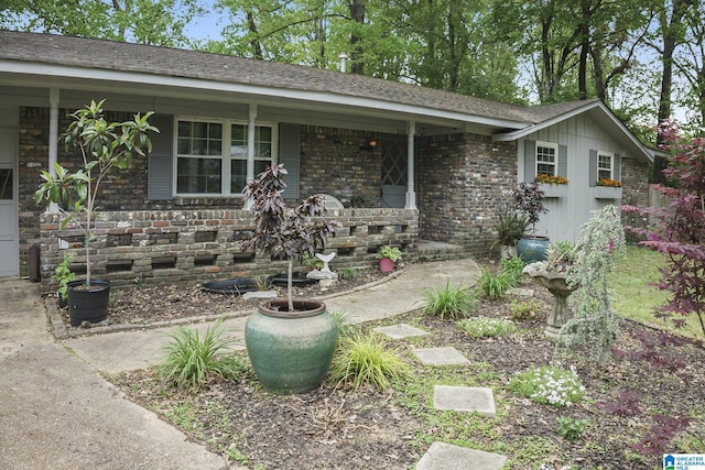 ranch-style home featuring a porch, brick siding, and stone siding