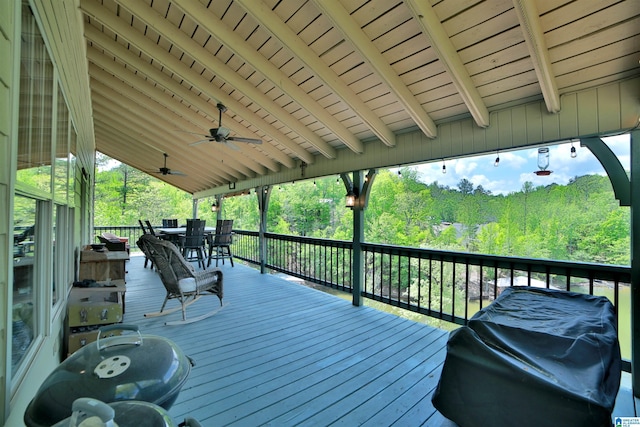 wooden deck featuring a ceiling fan, outdoor dining area, and a wooded view