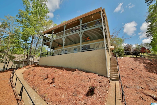 back of property with ceiling fan and stairs