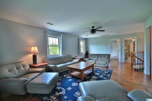 living room with visible vents, wood finished floors, and a ceiling fan