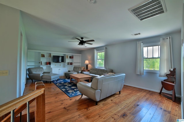 living room with hardwood / wood-style floors, visible vents, a ceiling fan, and baseboards