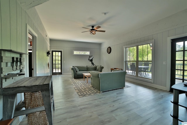 living room with a ceiling fan, baseboards, and light wood-style floors