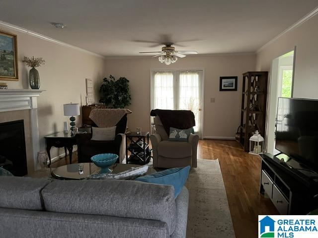 living room with wood finished floors, a healthy amount of sunlight, ornamental molding, and ceiling fan