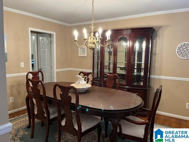 dining room with a chandelier, wood finished floors, baseboards, and ornamental molding