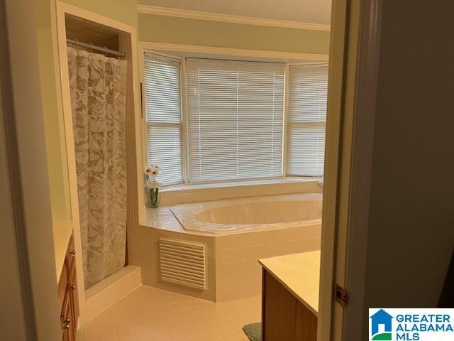 bathroom featuring tile patterned flooring, vanity, a shower with curtain, a bath, and crown molding