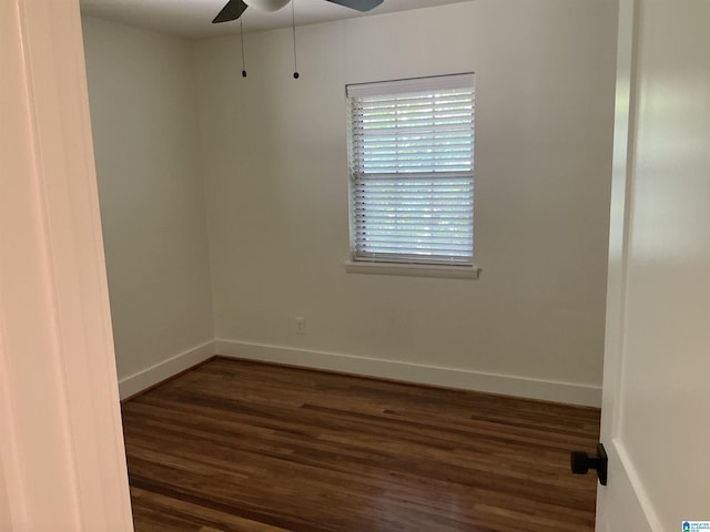 spare room with baseboards, dark wood finished floors, and ceiling fan
