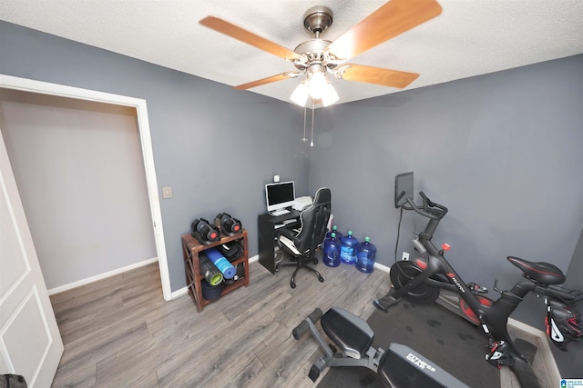 office featuring baseboards, a ceiling fan, wood finished floors, and a textured ceiling