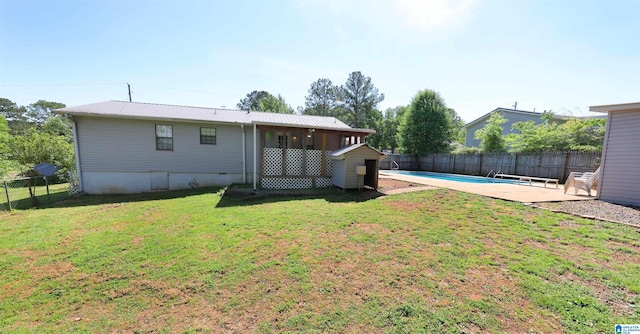 back of house featuring a fenced backyard, a fenced in pool, a yard, and metal roof