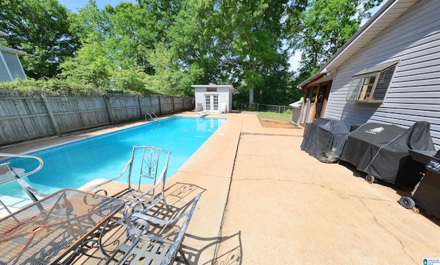view of pool with a fenced in pool, area for grilling, a fenced backyard, a patio area, and an outdoor structure