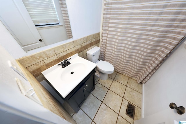 bathroom with tile patterned floors, visible vents, toilet, vanity, and tile walls