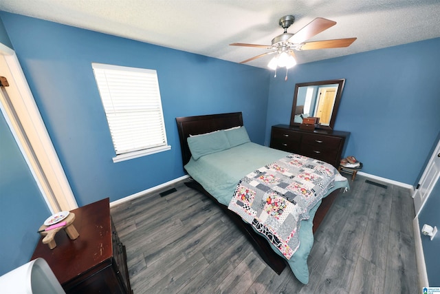 bedroom with dark wood finished floors, visible vents, a ceiling fan, and baseboards
