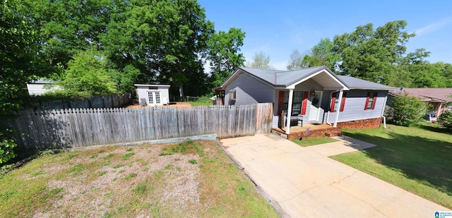 view of front of home with metal roof, concrete driveway, fence, an outdoor structure, and a front yard