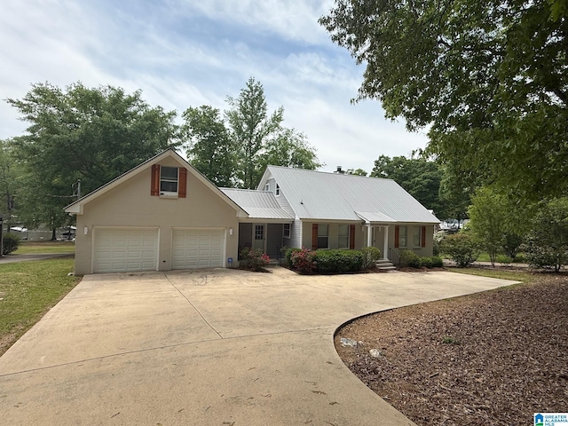 view of front of home with metal roof, concrete driveway, and a garage