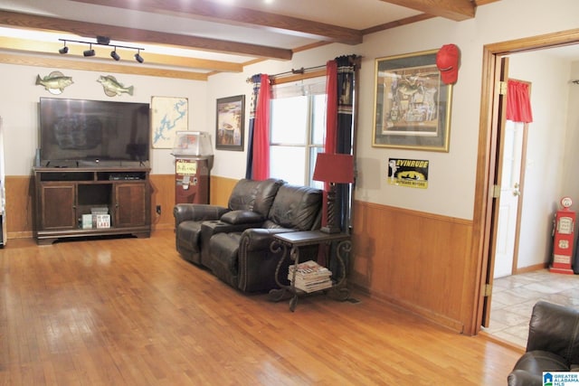 living area featuring beam ceiling, wood finished floors, wood walls, and a wainscoted wall