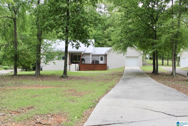 single story home featuring concrete driveway, metal roof, a front yard, an attached garage, and fence