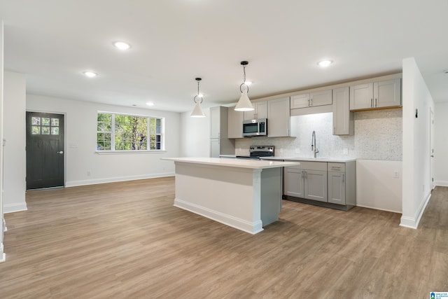 1515 Spring St, Alexander City, AL 35010 - kitchen with a sink, light wood-style floors, decorative backsplash, gray cabinetry, and appliances with stainless steel finishes
