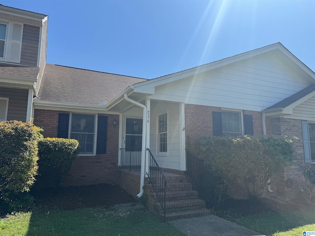 view of front facade with brick siding and roof with shingles
