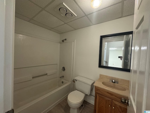 full bathroom with wood finished floors, vanity, bathtub / shower combination, a drop ceiling, and toilet