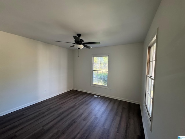 unfurnished room featuring dark wood finished floors, visible vents, a ceiling fan, and baseboards