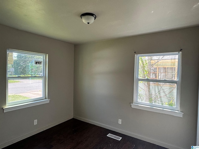 spare room with baseboards, visible vents, and dark wood-type flooring
